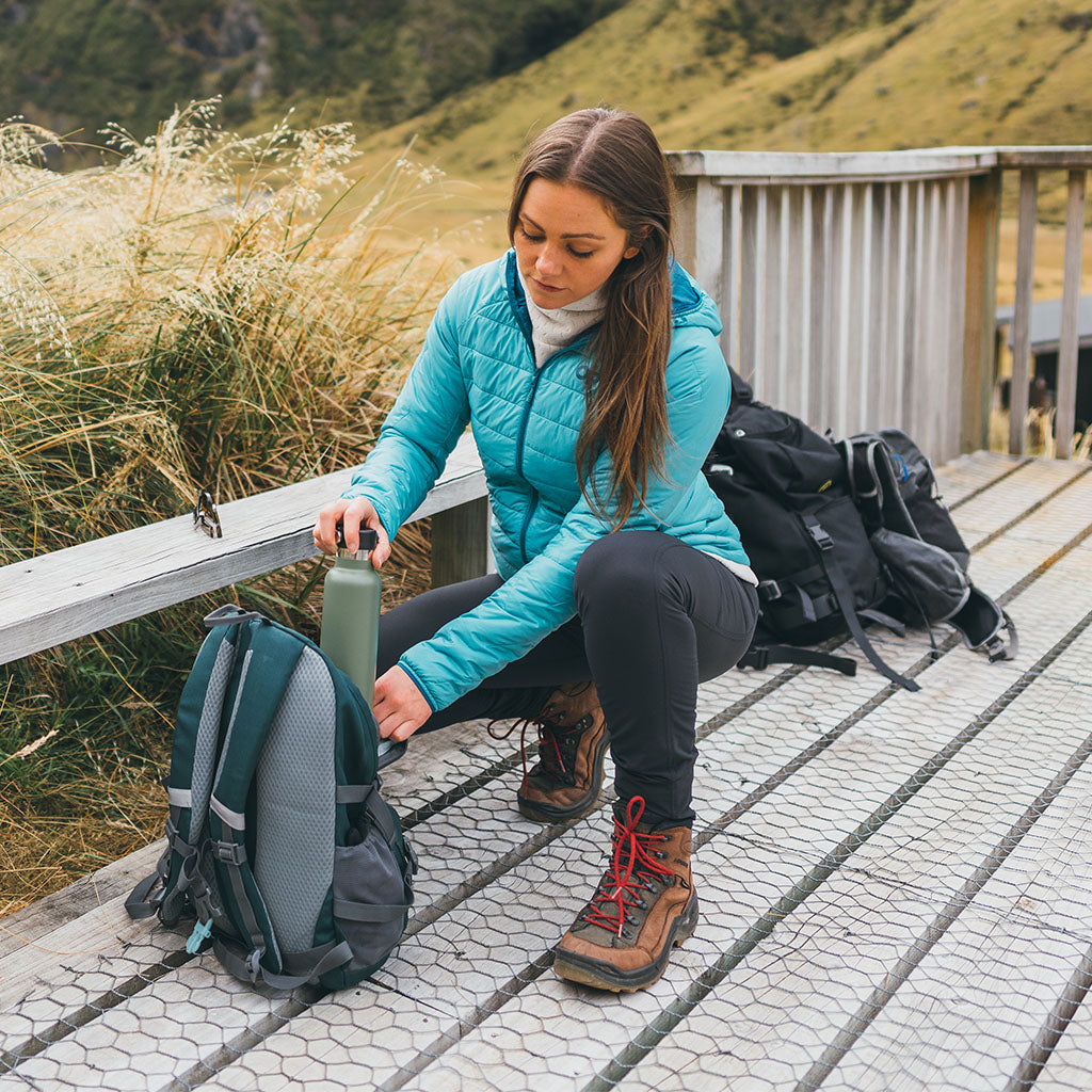 Female packing up her backpack wearing Outdoor Research Women's SuperStrand XT Hoodie Tidepool.