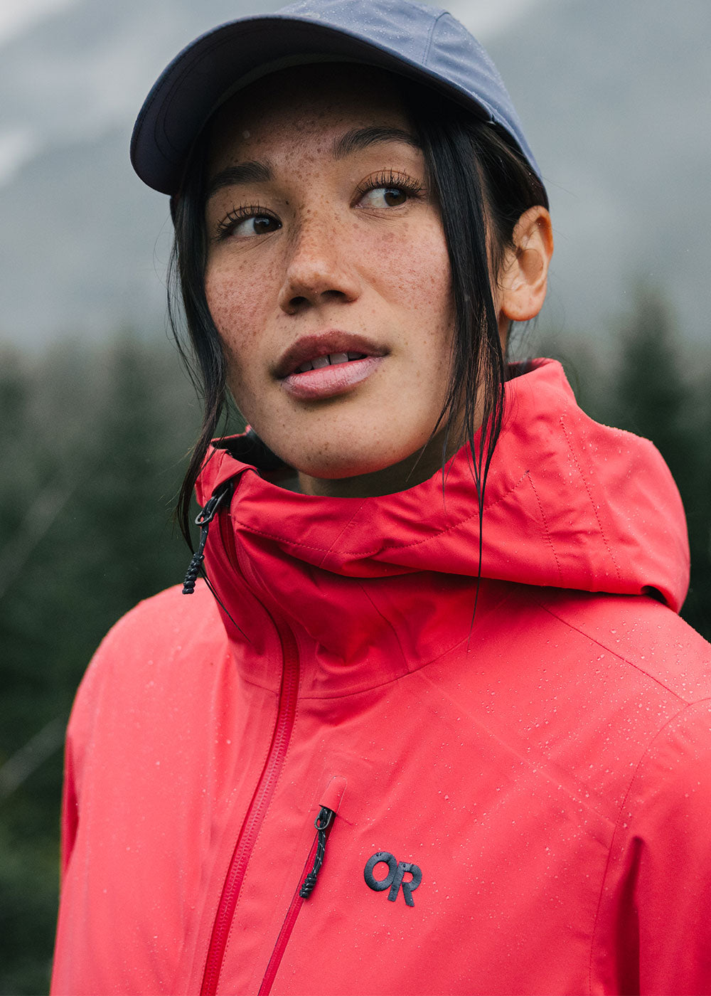 Woman looks and admires the nature and trees around her while wearing the Outdoor Research Aspire 3L Jacket.