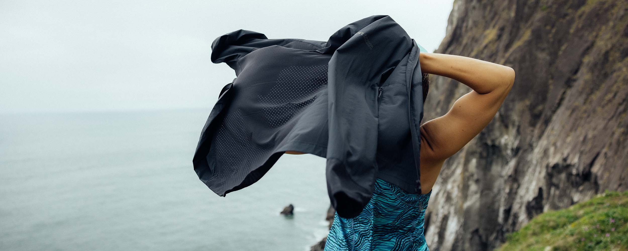 Image of a woman putting her Outdoor Research Deviator Wind Jacket in Black. 