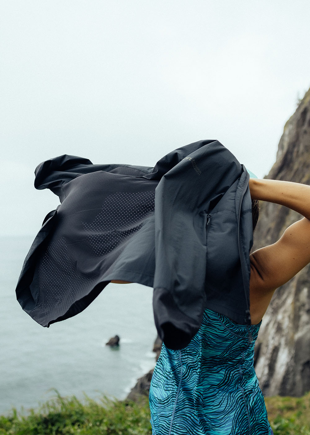 Image of a woman putting her Outdoor Research Deviator Wind Jacket in Black. 